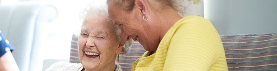 Female carer laughing with female resident banner 970x250.jpg