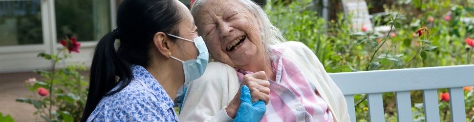 Female resident laughing with carer 970x250.jpg